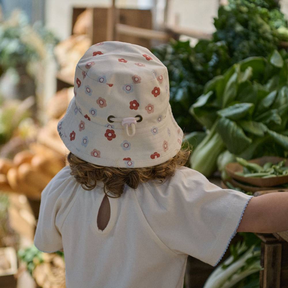 Back view of a child wearing a cotton bucket sunhat with a floral pattern. 