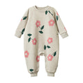 Beige baby onesie with pink floral patterns with domes on the legs on a white background