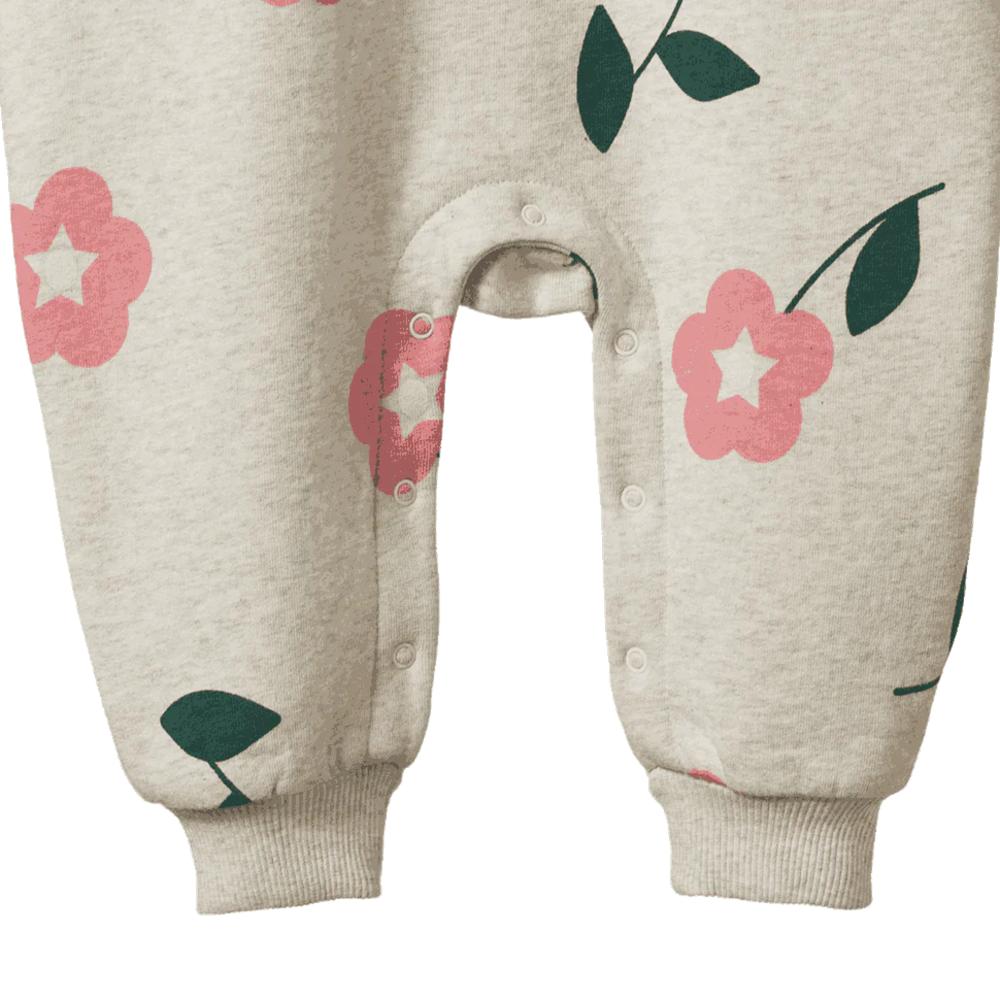 Close-up of a baby romper with floral patterns and domes between the legs on a white background