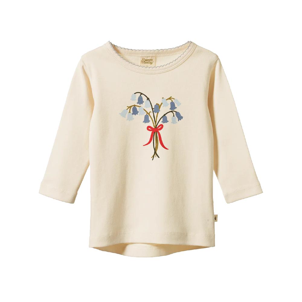 Cotton cream coloured long-sleeve shirt with bluebell floral design and red bow on a white background