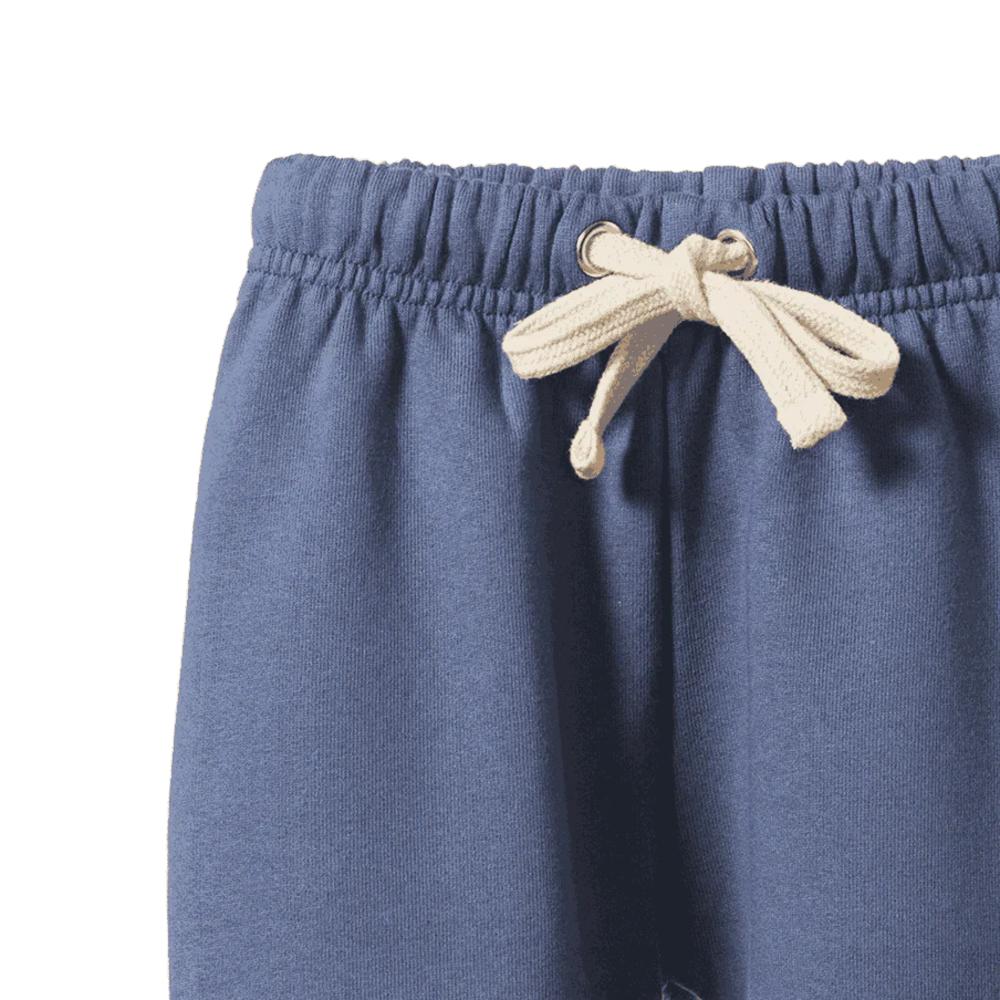 Close-up of blue sweatpants with a beige drawstring on a white background