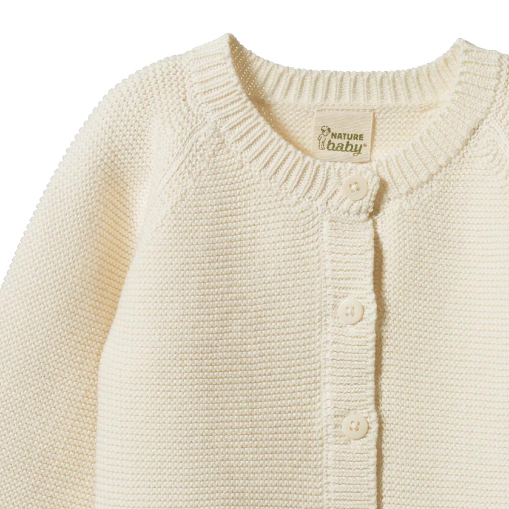 Close-up of a cream-colored baby knitted cardigan with buttons, featuring 'Nature Baby' branding.