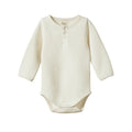 Cream baby onesie with waffle texture with long sleeves on a white background