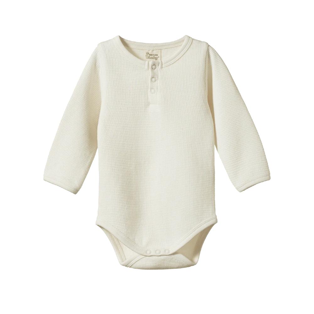 Cream baby onesie with waffle texture with long sleeves on a white background