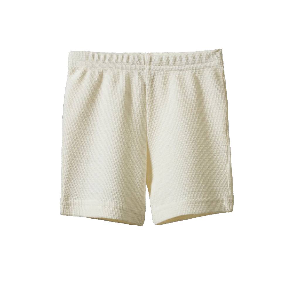 A pair of cream-colored waffle-knit shorts with an elastic waistband, shown flat against a solid white background.