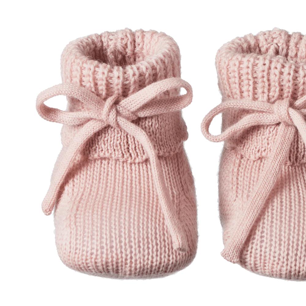Close-up on a pair of pink knitted baby booties with bows on a white background