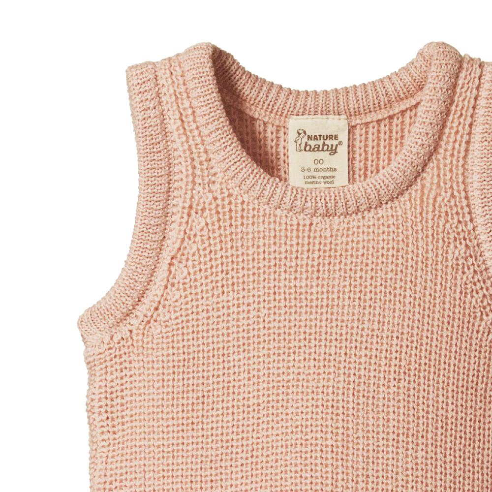 Close-up of a pink merino wool knitted baby vest with 'Nature Baby' label on a white background