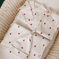 Set of white with raspberry pattern baby clothing set and blanket bundle  in a woven moses basket