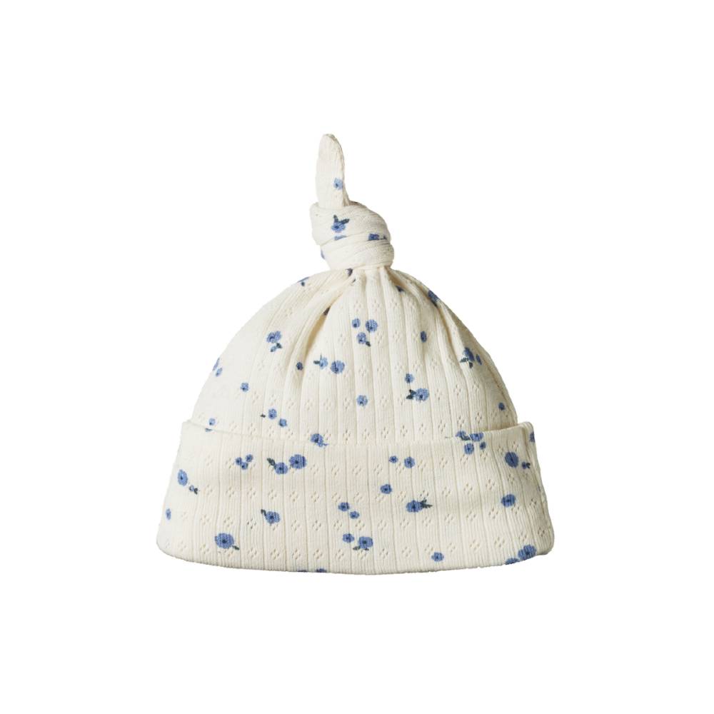 White cotton pointelle baby hat with blue floral patterns on a white background