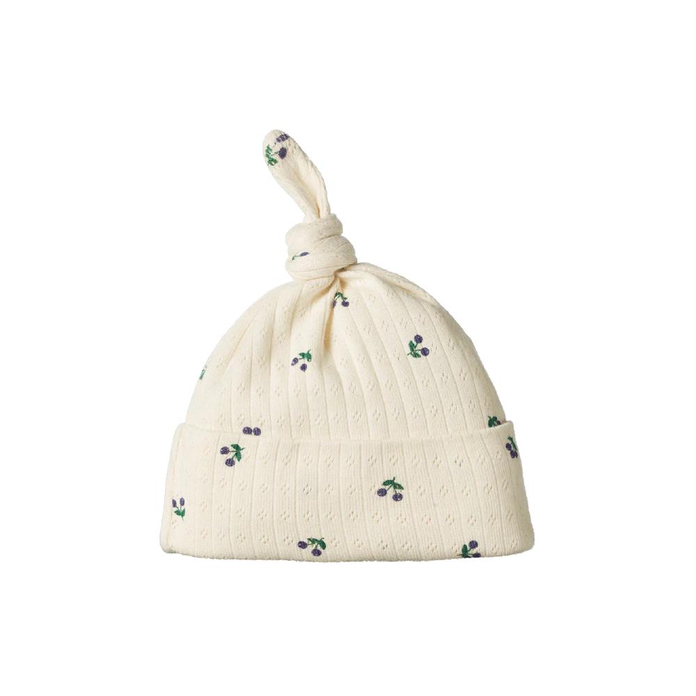 Cream-colored pointelle fabric baby hat with purple berry patterns on a white background