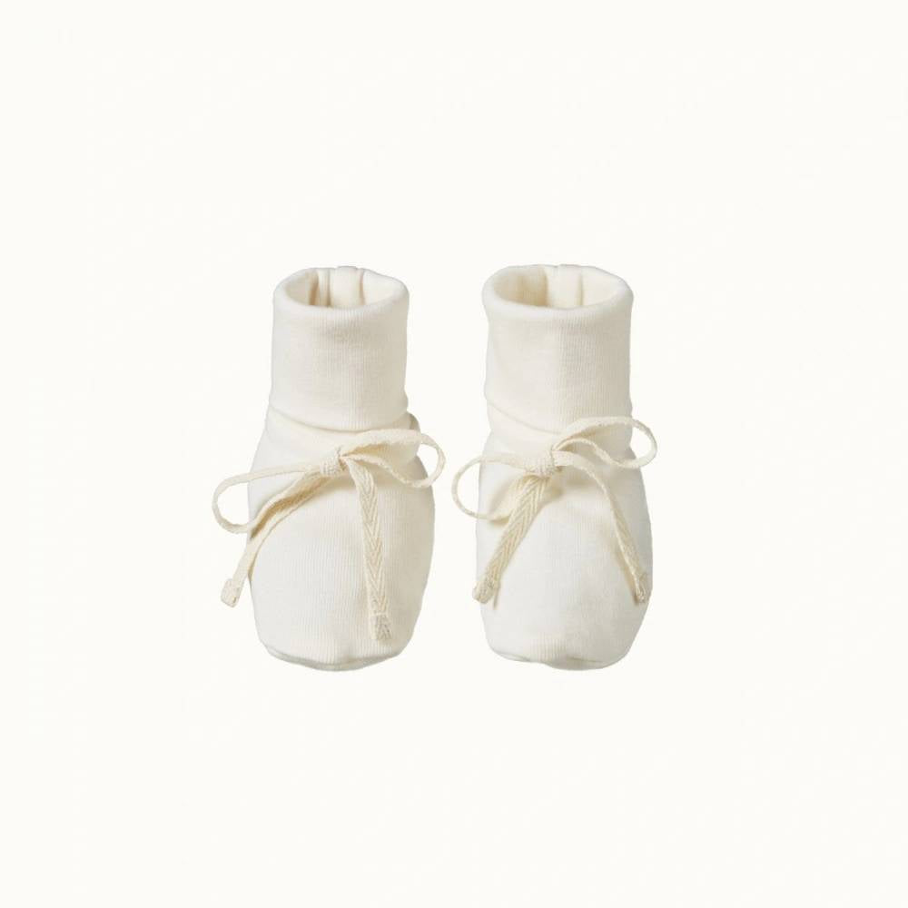 Pair of organic cotton white baby booties with cuffs and calico bows on front on a white background