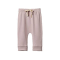 A pair of cotton drawstring pants in a dusty lilac color, featuring a cream-colored drawstring at the elastic waistband and ribbed cuffs at the ankles, shown against a plain white background.