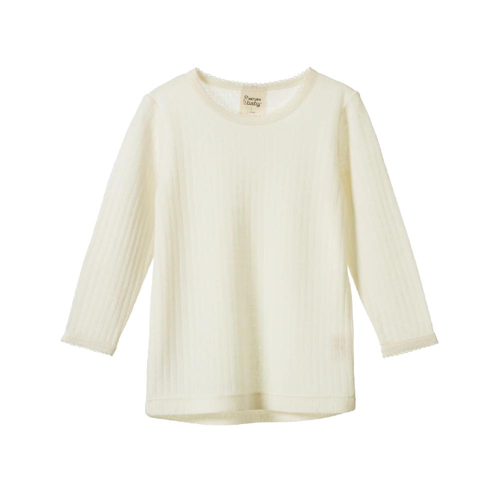 Cream-colored organic merino wool long-sleeve pointelle top on a white background