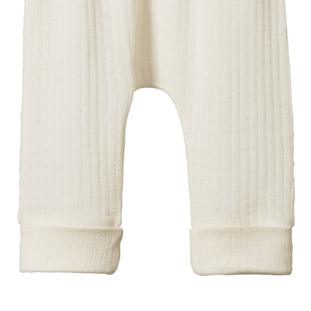 Close-up of cream-colored merino pointelle baby pants with cuff on a white background