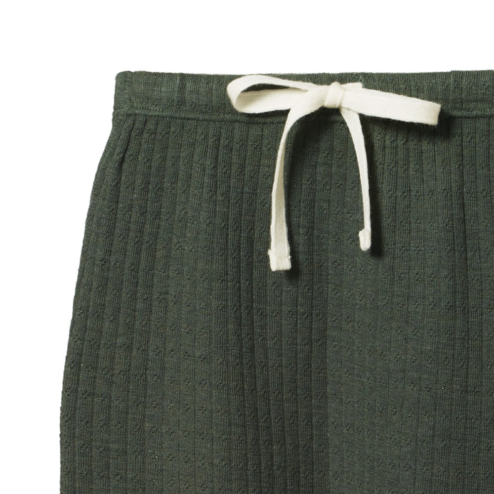 Close-up of forest green pointelle merino wool textured pants with a white drawstring on a white background