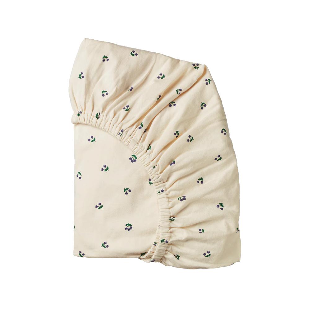 Cream coloured organic cotton jersey fitted sheet with small purple berry pattern on a white background