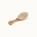 Beige wooden baby brush with natural goat bristles on a white background