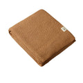 Caramel brown woolen knitted blanket with a brand label on a white background