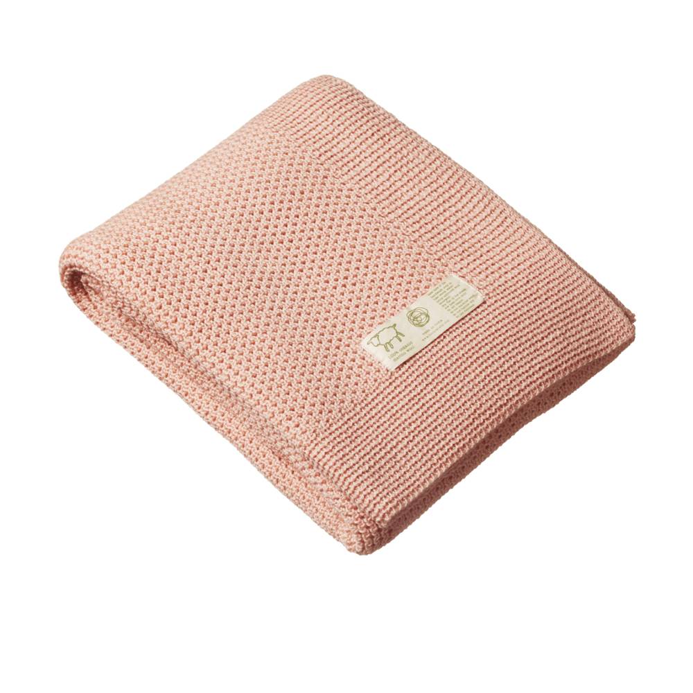 Pink merino wool knitted blanket with a white brand label on a white background