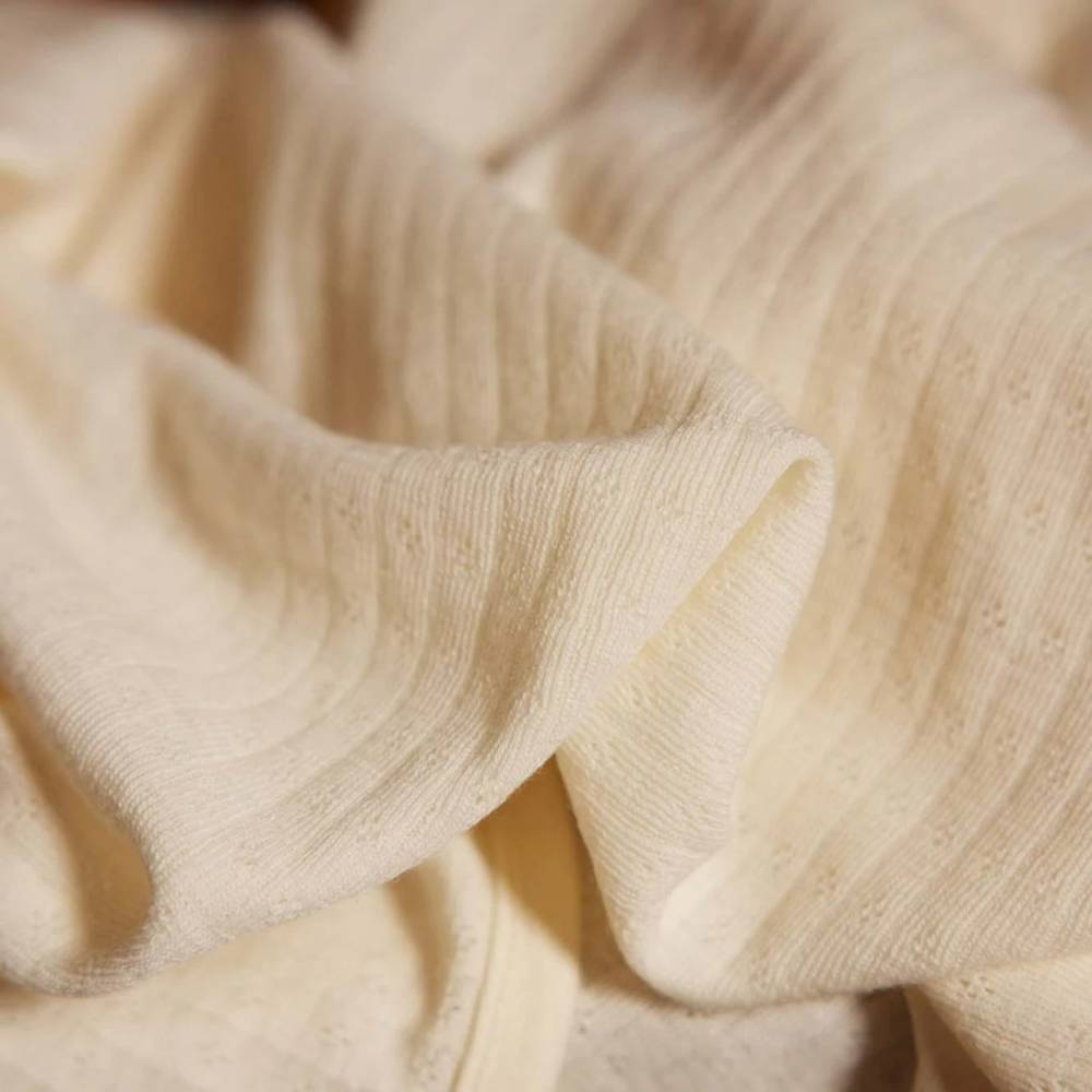 Close-up of cream merino pointelle fabric with a soft texture