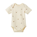 A short-sleeve baby bodysuit in cream with a scattered print of small brown instruments, shown flat against a white background.