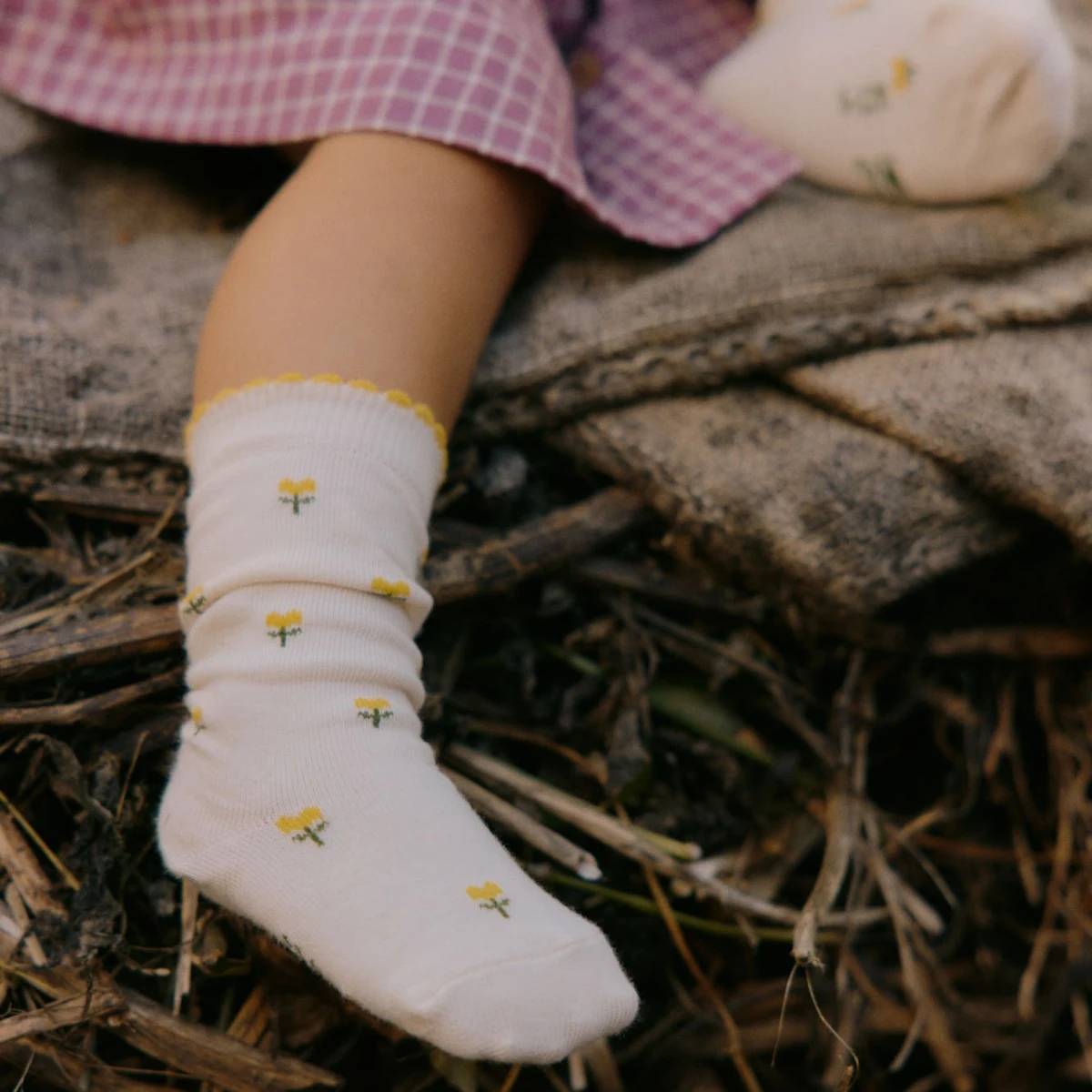 White socks with yellow floral pattern and yellow trim worn by a child on a natural background