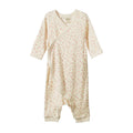 A baby long-sleeve footless onesie in cream cotton muslin with a tiny pink and green floral print, featuring a wrap-style front and snap closures.