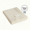 Cream merino wool knitted blanket with a white brand label on a white background, featuring the OHbaby! Awards logo.