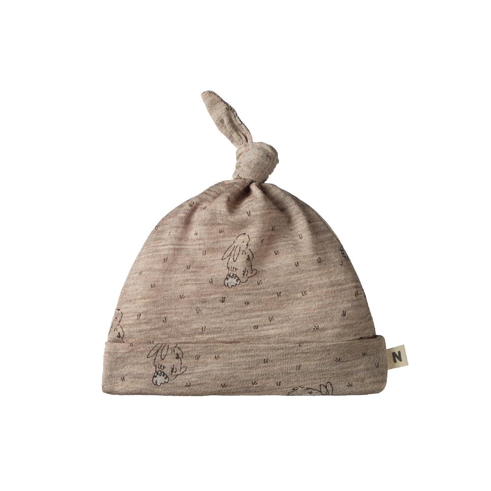Beige merino baby hat with soft bunny designs and top knot on a white background