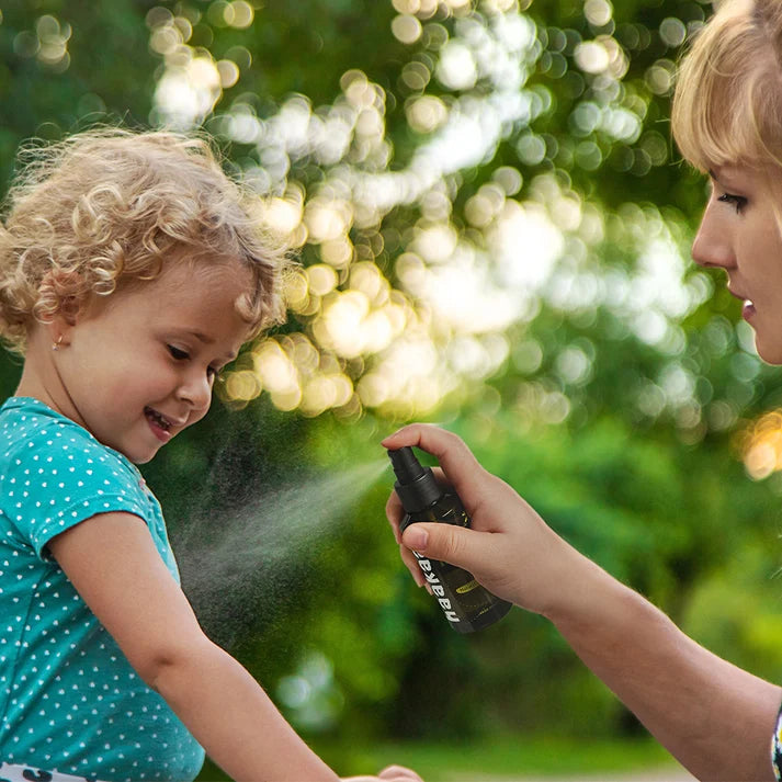 Mother spraying child's arm with insect repellent