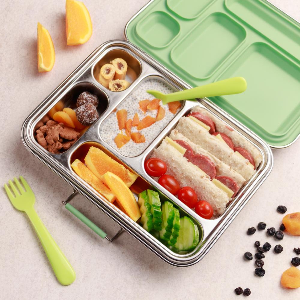 Bento box with compartments filled with food, including sandwiches and fruits, on a light surface.