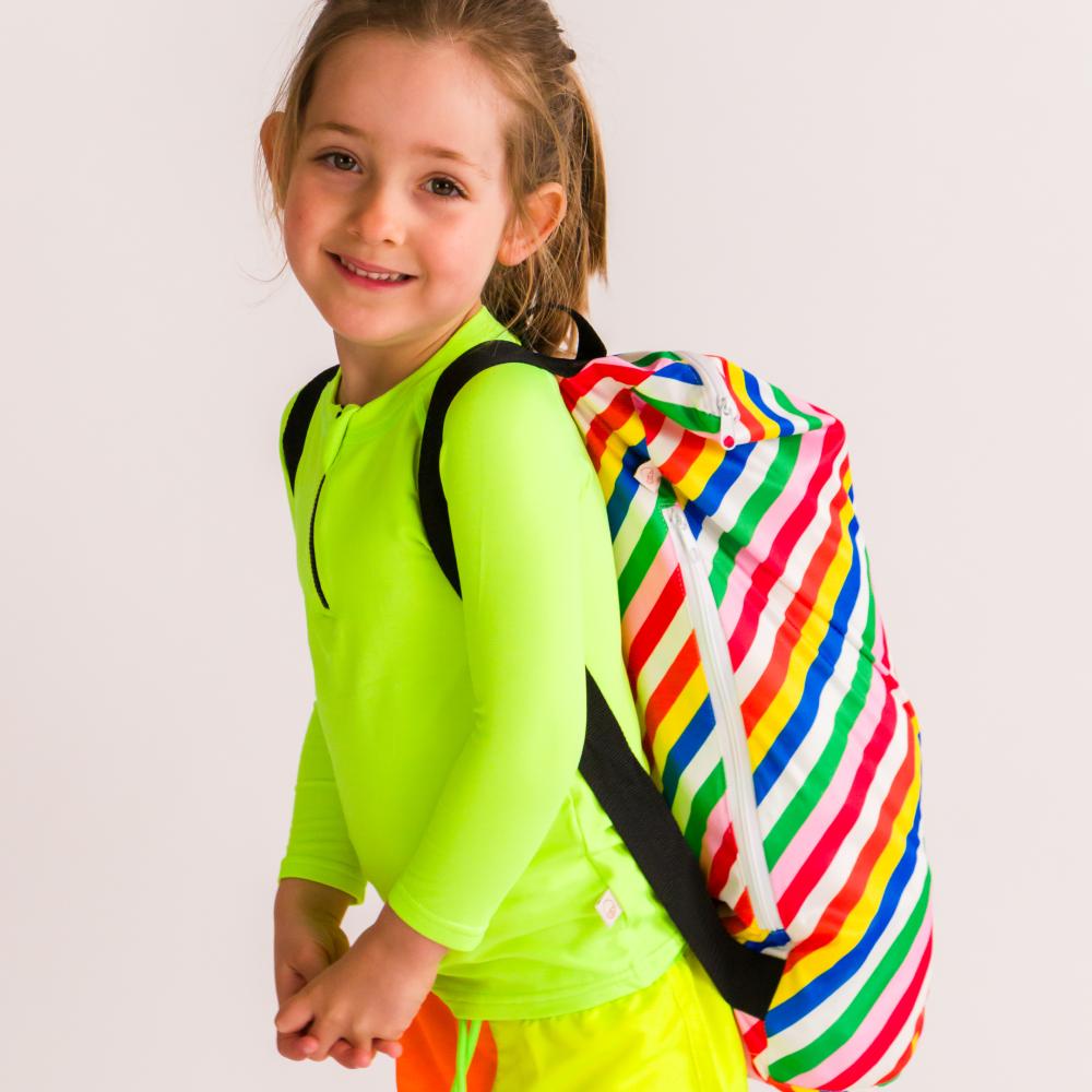 Child wearing a colorful striped swim bag on a plain background