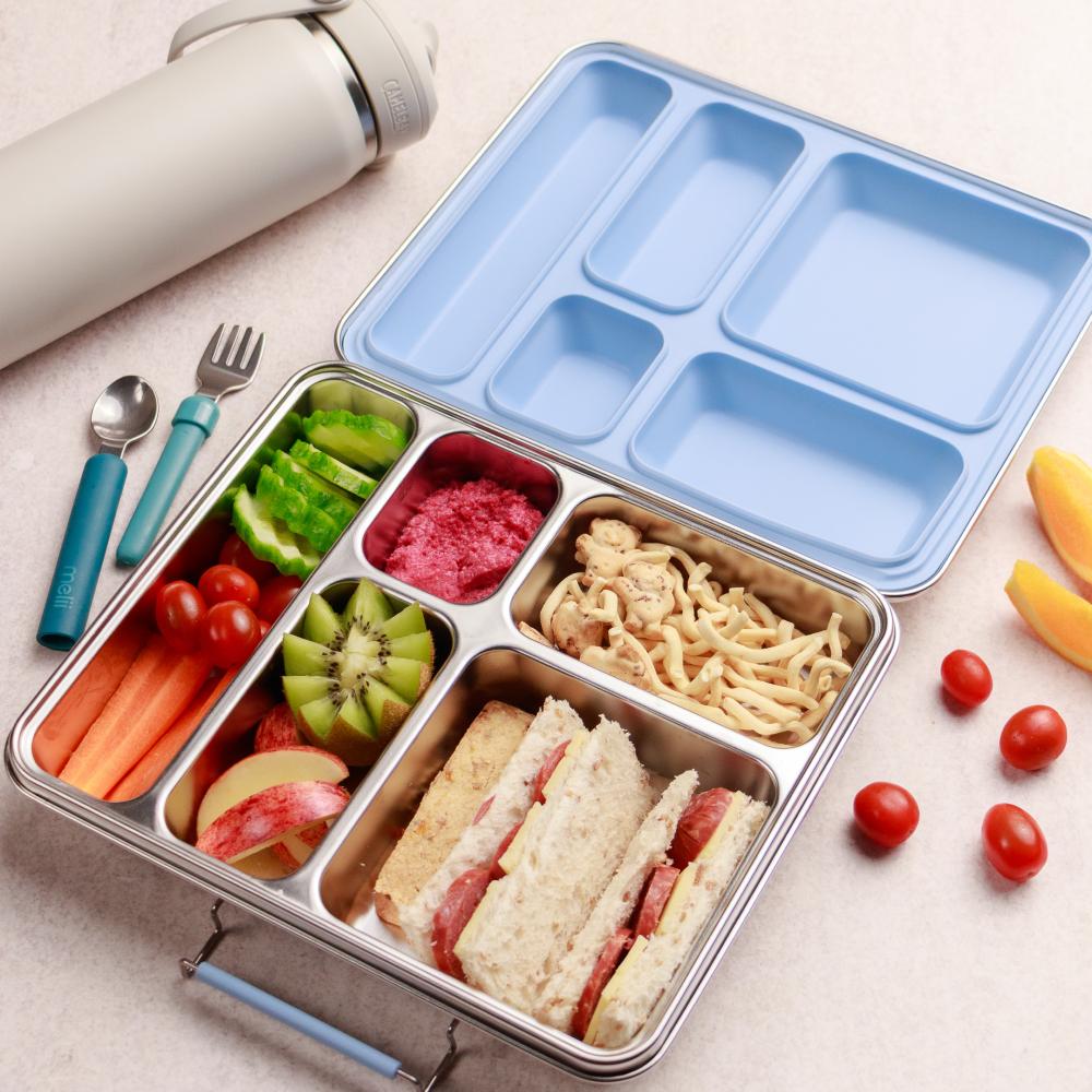 Jumbo large Bento box with compartments filled with food items on a light surface.