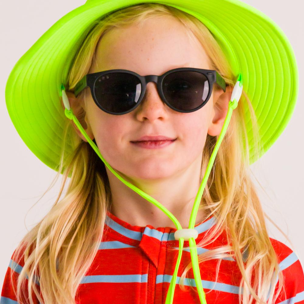 Person wearing a bright green hat and round black sunglasses with a red and blue striped shirt.
