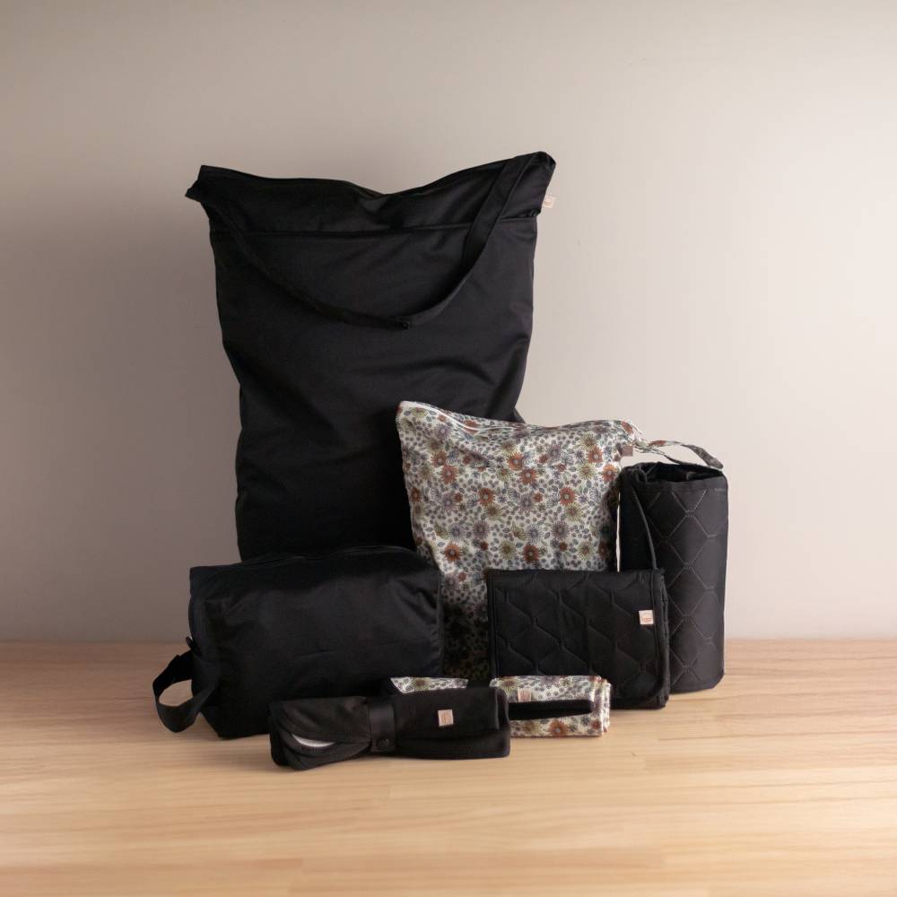 Collection of black and patterned wet bags on a wooden surface with a neutral background