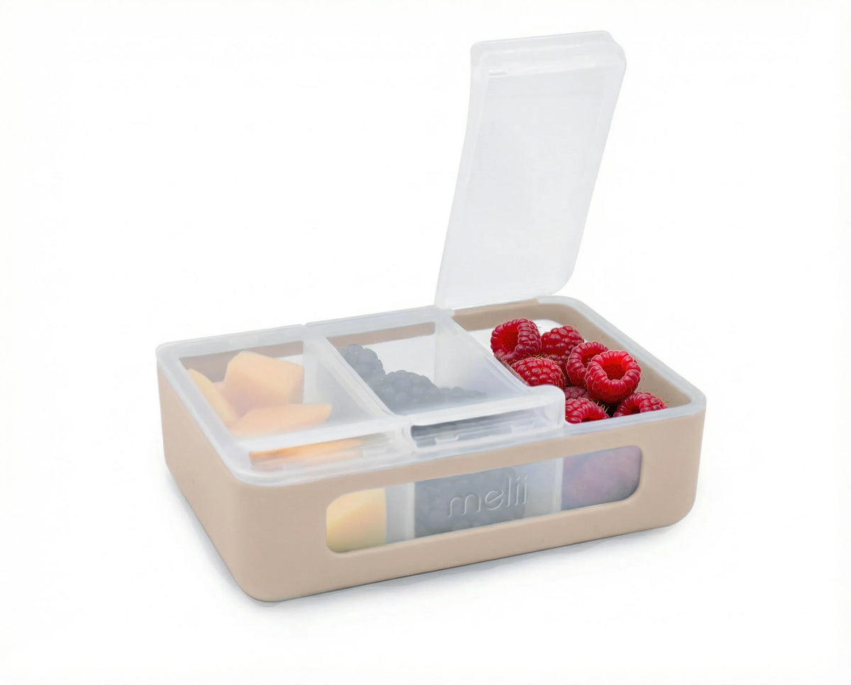 Beige bento box with compartments containing fruits and vegetables on a white background