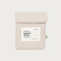 A folded light beige bottom sheet with a white paper label reading 'babu basics. bottom sheet' and a small side tag, shown on a plain light gray background.