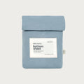 A folded light blue bottom sheet in a matching fabric pouch with a white label reading 'babu basics. bottom sheet' on a light gray background.