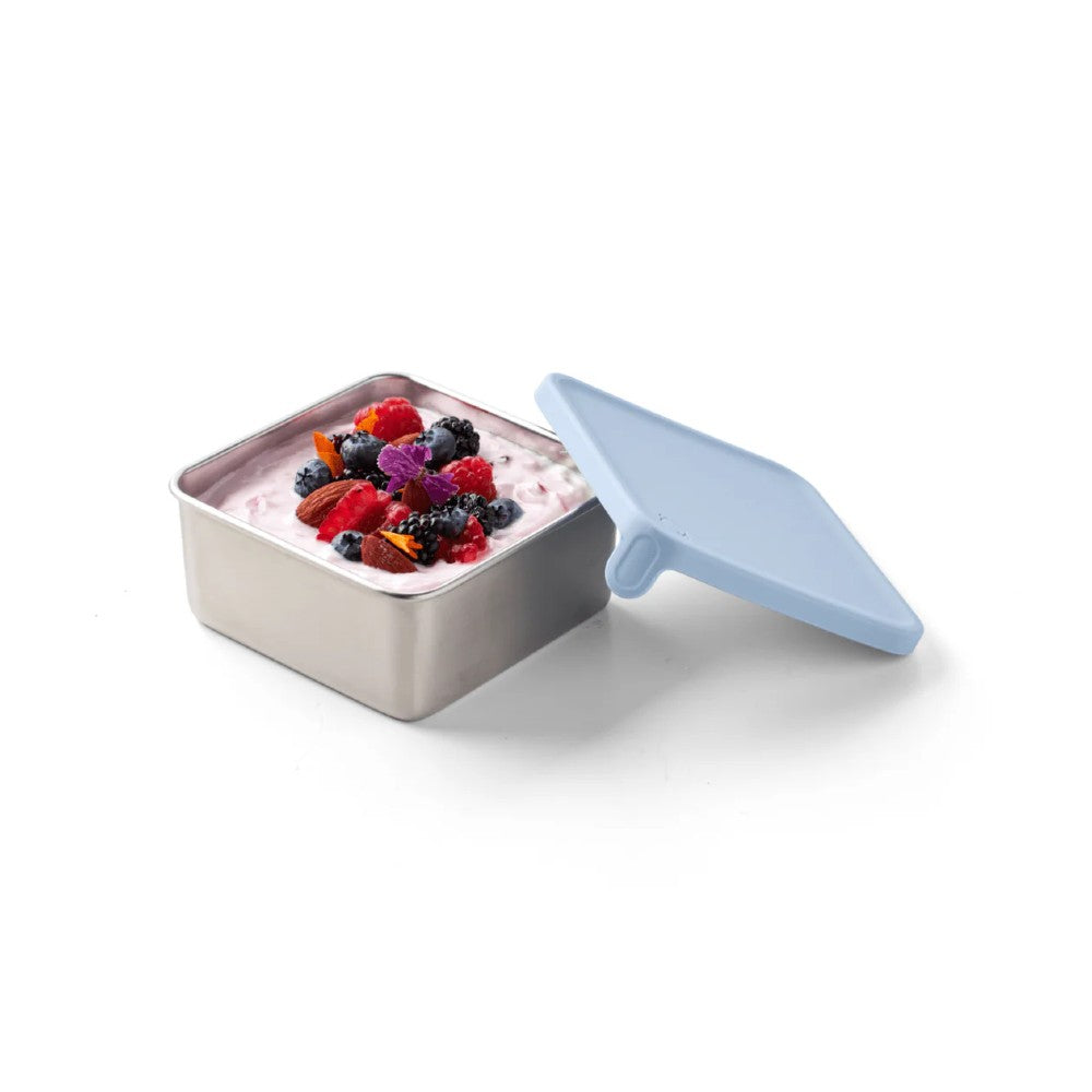 Rectangular container with a blue lid filled with yogurt and berries on a white background
