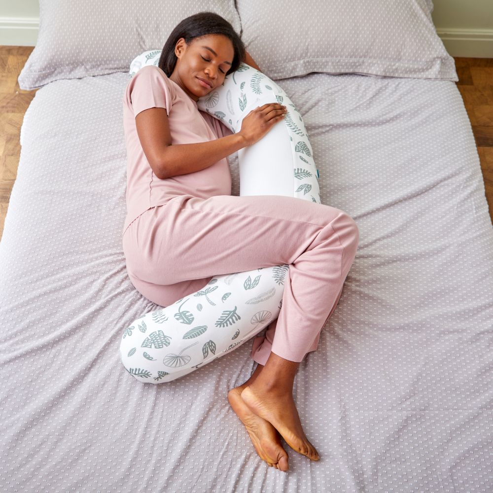 Woman sleeping on a bed with a leaf print pregnancy U-shaped body pillow