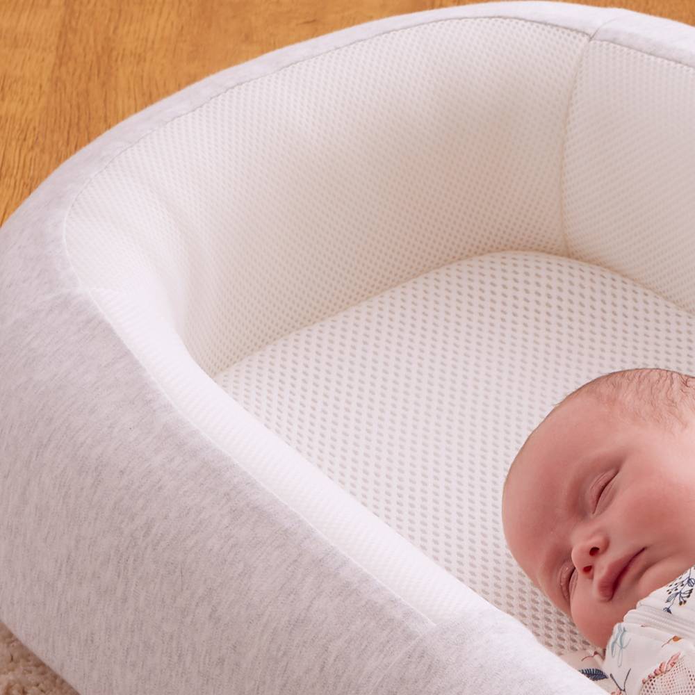 Newborn baby sleeping in a white crib with a soft texture.