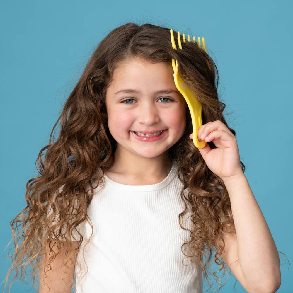 Child using yellow Pump Haircare comb against blue background.