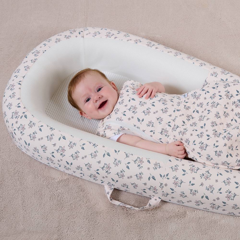 Baby wrapped in a floral-patterned sleep nest.