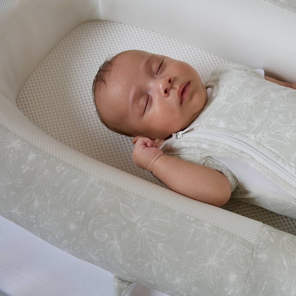 Baby sleeping in a mesh base Purflo baby bed with a white background