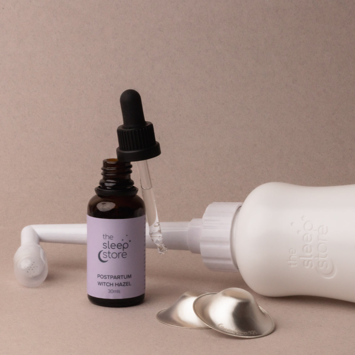 Bottle of 'The Sleep Store' postpartum witch hazel with dropper on a beige background