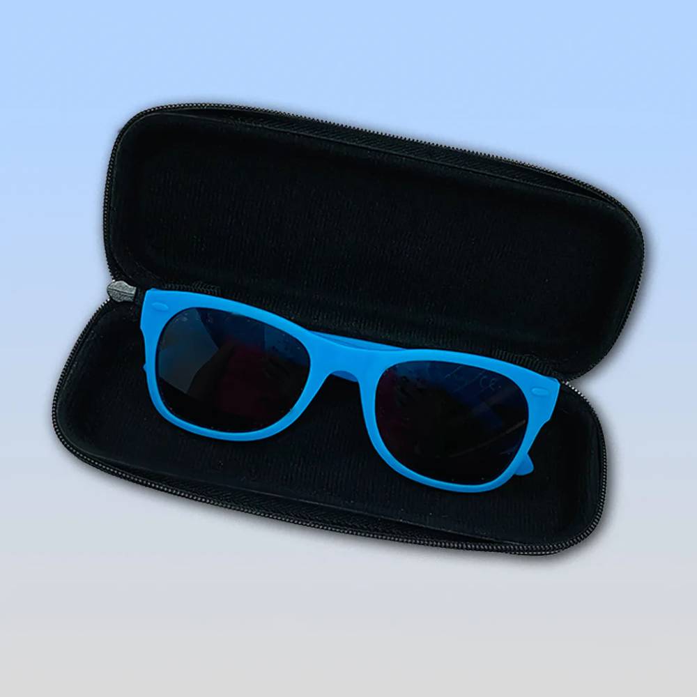 Bright blue sunglasses with dark lenses resting inside an open black zippered hard case against a light blue gradient background.
