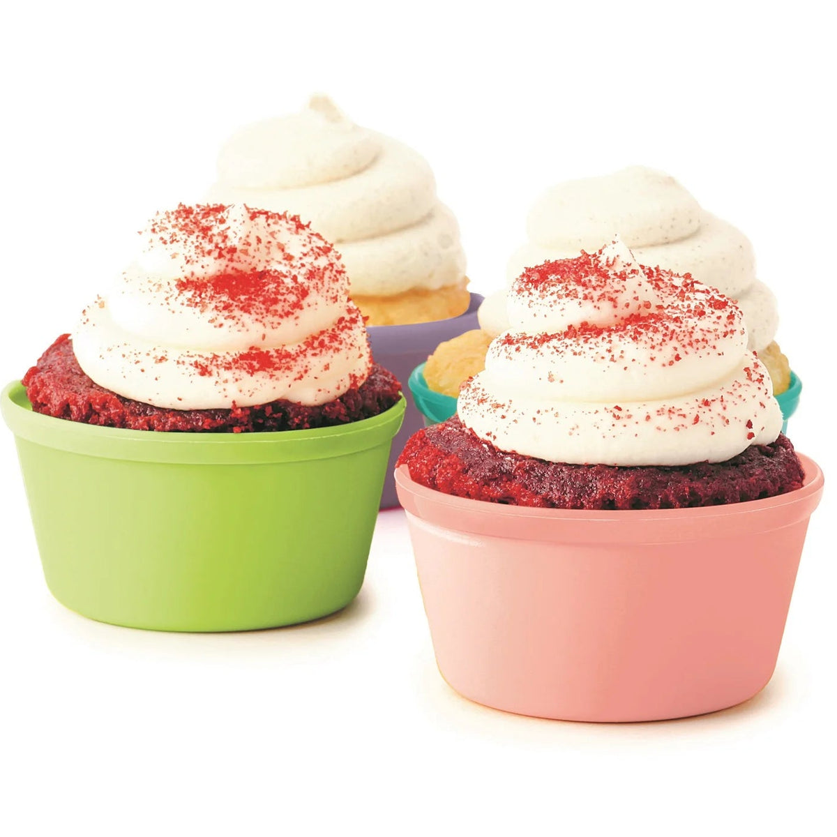 Three cupcakes in rainbow silcone baking cups on a white background. The front cupcake is in a pink cup with white frosting and red sprinkles, the left cupcake is in a green cup with white frosting and red sprinkles, and a third cupcake is partially visible behind them in a purple cup.