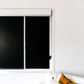 Sleepy Sunday black blackout blinds against white wall.