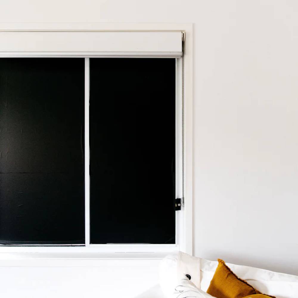 Sleepy Sunday black blackout blinds against white wall.