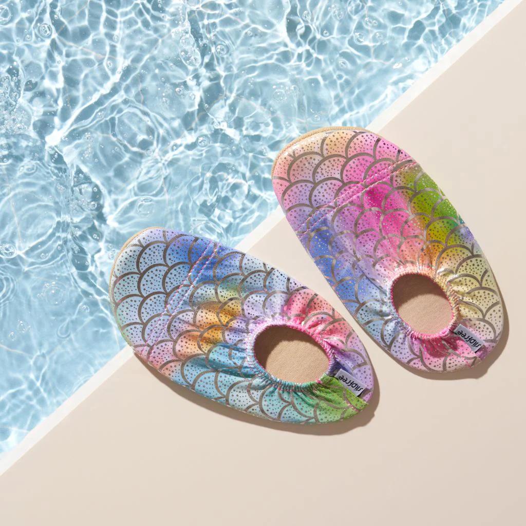 Colorful metallic mermaid scale-patterned slipfree watershoes on a ledge with water in the background